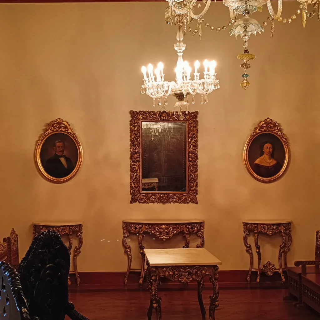 Salón con retratos y espejo dorado en Casa Castilla